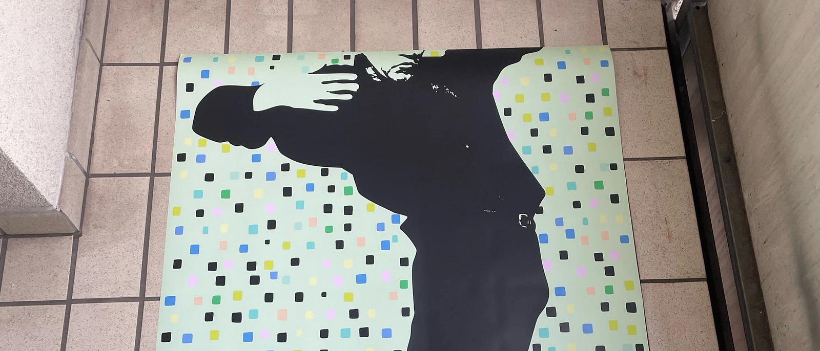 Black standing silhouette on a pale green dotted poster.