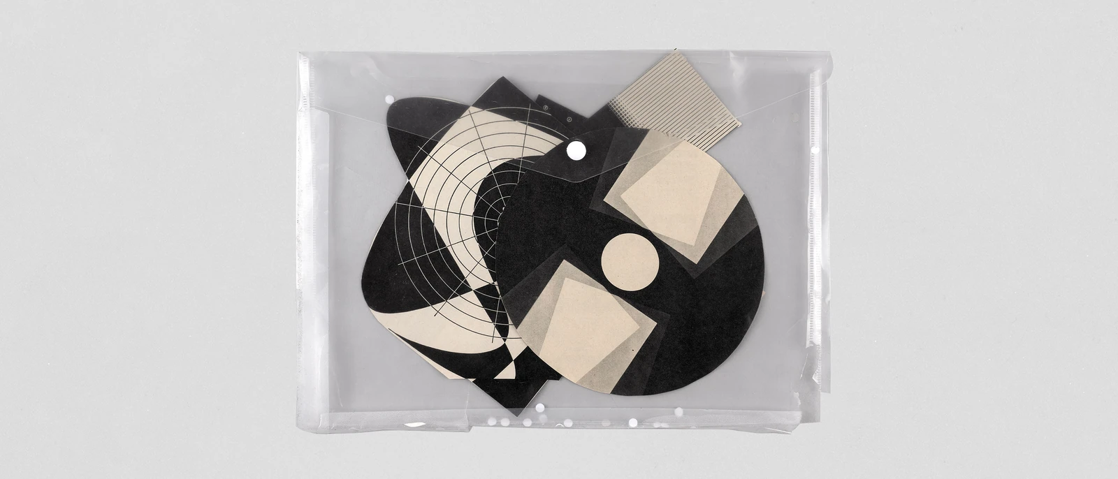 Transparent sleeve with black-and-white geometric paper cut-outs.